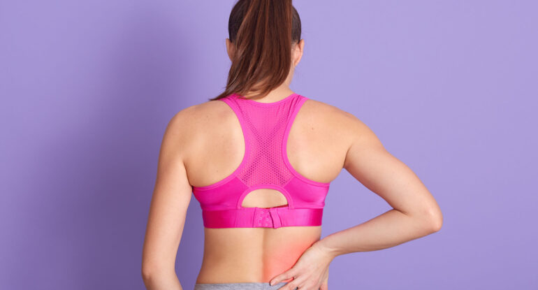Rear view of a woman in activewear experiencing lower back pain